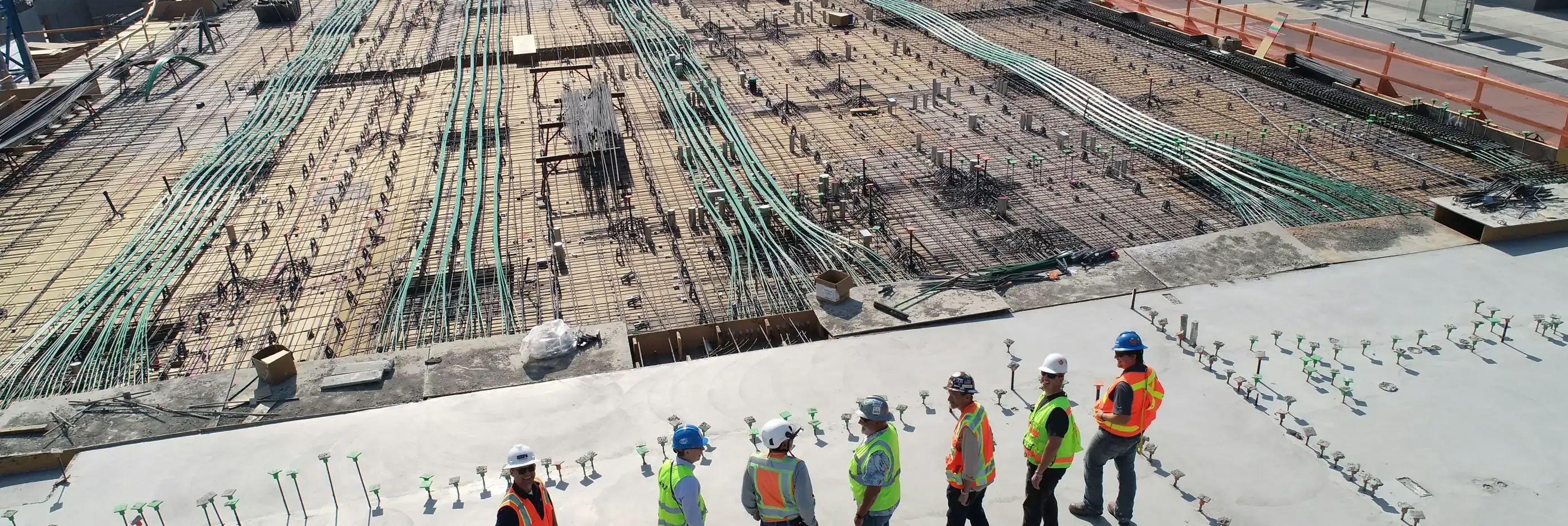 Construction crew on a slab looking over a rebar deck before the pour